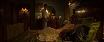 Movie still from “The Hand of God” (2021), directed by Paolo Sorrentino – A man standing next to an older woman in a bed; Wide shot, Over the shoulder angle