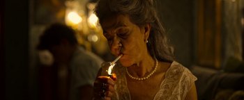 Movie still from “The Hand of God” (2021), directed by Paolo Sorrentino – An older woman lighting a candle in a candle holder; Close Up shot, Low angle