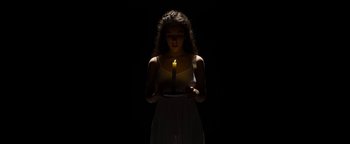 Movie still from “The Hand of God” (2021), directed by Paolo Sorrentino – A woman holding a lit candle in a dark room; Medium shot, High angle