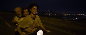 Movie still from “The Hand of God” (2021), directed by Paolo Sorrentino – A man and a woman riding a motorcycle at night; Medium shot, Over the shoulder angle