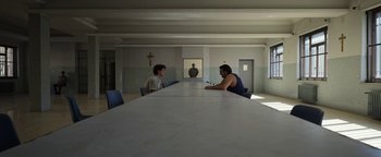Movie still from “The Hand of God” (2021), directed by Paolo Sorrentino – Two men sitting at a long table in front of a mirror; Wide shot, Over the shoulder angle