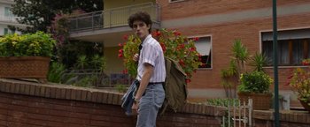 Movie still from “The Hand of God” (2021), directed by Paolo Sorrentino – A young man standing in front of a brick building; Medium shot, Low angle