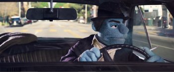 Movie still from “The Happytime Murders” (2018), directed by Brian Henson – A person in a car wearing a suit and a hat; Medium shot, Low angle