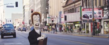 Movie still from “The Happytime Murders” (2018), directed by Brian Henson – A man in a black suit holding a briefcase on a street; Medium shot, Low angle