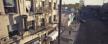 Movie still from “The Happytime Murders” (2018), directed by Brian Henson – A person walking down a street next to a building; Extreme Wide shot, High angle