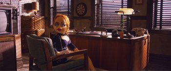 Movie still from “The Happytime Murders” (2018), directed by Brian Henson – A doll sitting on a chair in a room; Wide shot, Over the shoulder angle