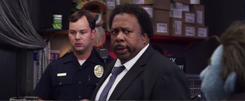 Movie still from “The Happytime Murders” (2018), directed by Brian Henson – A man in a suit and tie holding a microphone; Close Up shot, Over the shoulder angle