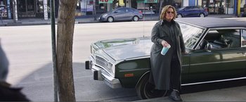 Movie still from “The Happytime Murders” (2018), directed by Brian Henson – A woman standing next to an old car on the side of the road; Wide shot, High angle