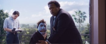 Movie still from “The Happytime Murders” (2018), directed by Brian Henson – A man standing next to another man in a suit and tie; Medium shot, Low angle