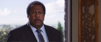 Movie still from “The Happytime Murders” (2018), directed by Brian Henson – A man in a suit and tie standing in front of a window; Close Up shot, Over the shoulder angle