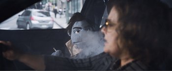 Movie still from “The Happytime Murders” (2018), directed by Brian Henson – A person in a car with smoke coming out of their mouth; Close Up shot, Over the shoulder angle