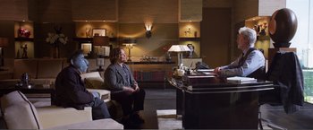 Movie still from “The Happytime Murders” (2018), directed by Brian Henson – A woman sitting on a chair in front of a desk; Wide shot, High angle