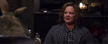 Movie still from “The Happytime Murders” (2018), directed by Brian Henson – A woman in a striped jacket is sitting in front of a bottle; Close Up shot, Over the shoulder angle