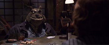 Movie still from “The Happytime Murders” (2018), directed by Brian Henson – A stuffed dog sitting at a table in front of a bottle of beer; Medium shot, Over the shoulder angle