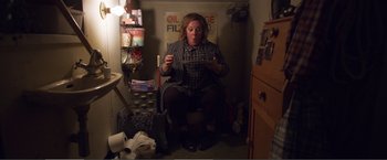 Movie still from “The Happytime Murders” (2018), directed by Brian Henson – A woman sitting on a toilet in a room; Wide shot, Overhead angle
