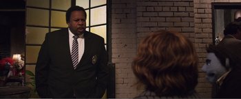 Movie still from “The Happytime Murders” (2018), directed by Brian Henson – A man wearing a suit and tie standing next to a woman; Medium shot, Over the shoulder angle
