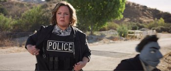 Movie still from “The Happytime Murders” (2018), directed by Brian Henson – A woman in a police vest is walking down the street; Medium shot, Over the shoulder angle