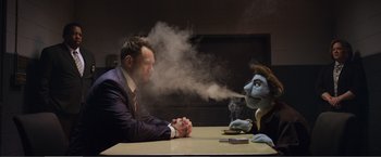 Movie still from “The Happytime Murders” (2018), directed by Brian Henson – A man sitting at a table next to a puppet smoking; Medium shot, Over the shoulder angle