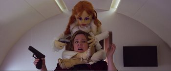 Movie still from “The Happytime Murders” (2018), directed by Brian Henson – A woman is sitting on the head of a doll; Medium shot, Low angle