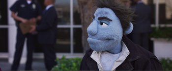 Movie still from “The Happytime Murders” (2018), directed by Brian Henson – A person with a blue face and black hair; Close Up shot, Over the shoulder angle
