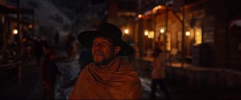 Movie still from “The Harder They Fall” (2021), directed by Jeymes Samuel – A man wearing a black hat and a brown cape; Medium shot, Low angle