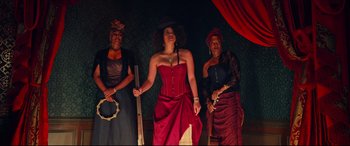 Movie still from “The Harder They Fall” (2021), directed by Jeymes Samuel – A group of three women standing next to each other on a stage; Medium shot, Low angle