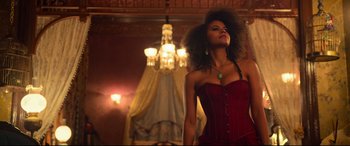 Movie still from “The Harder They Fall” (2021), directed by Jeymes Samuel – A woman in a red corset standing next to a chandelier; Medium shot, Low angle