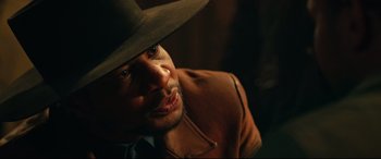Movie still from “The Harder They Fall” (2021), directed by Jeymes Samuel – A person wearing a cowboy hat; Close Up shot, Over the shoulder angle