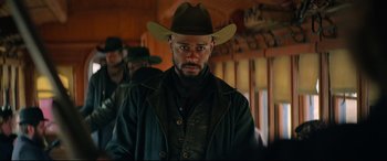 Movie still from “The Harder They Fall” (2021), directed by Jeymes Samuel – A man wearing a cowboy hat and a leather jacket; Close Up shot, Over the shoulder angle