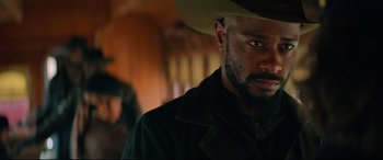 Movie still from “The Harder They Fall” (2021), directed by Jeymes Samuel – A person wearing a cowboy hat; Close Up shot, Over the shoulder angle