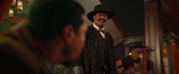 Movie still from “The Harder They Fall” (2021), directed by Jeymes Samuel – An older man wearing a black hat and a brown jacket; Medium shot, Low angle