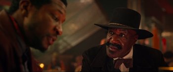 Movie still from “The Harder They Fall” (2021), directed by Jeymes Samuel – A man in a suit and a black hat is talking to another man in a black hat; Close Up shot, Over the shoulder angle