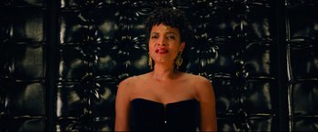 Movie still from “The Harder They Fall” (2021), directed by Jeymes Samuel – A woman in a strapless black dress and gold earrings; Close Up shot, Low angle