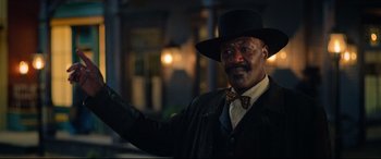 Movie still from “The Harder They Fall” (2021), directed by Jeymes Samuel – A man wearing a black hat and a black jacket; Medium shot, Low angle