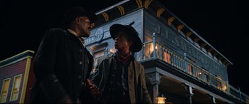 Movie still from “The Harder They Fall” (2021), directed by Jeymes Samuel – A couple of men standing next to each other on a street; Medium shot, Low angle