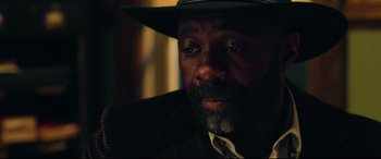 Movie still from “The Harder They Fall” (2021), directed by Jeymes Samuel – A person wearing a suit and a hat; Close Up shot, Over the shoulder angle
