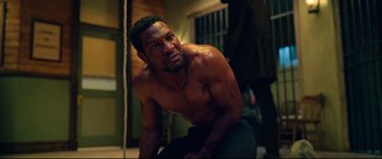 Movie still from “The Harder They Fall” (2021), directed by Jeymes Samuel – A man with no shirt is posing for a picture; Medium shot, Low angle