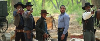 Movie still from “The Harder They Fall” (2021), directed by Jeymes Samuel – A group of men standing next to each other holding guns; Medium shot, Low angle