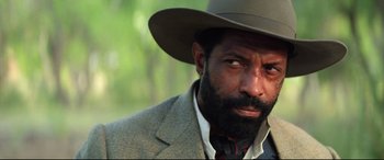 Movie still from “The Harder They Fall” (2021), directed by Jeymes Samuel – A person wearing a hat; Close Up shot, Low angle