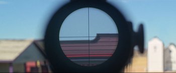 Movie still from “The Harder They Fall” (2021), directed by Jeymes Samuel – A rifle scope with a view of a building in the background; Extreme Close Up shot, Overhead angle