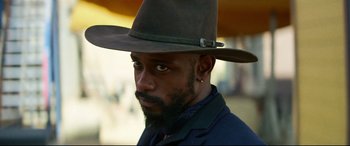 Movie still from “The Harder They Fall” (2021), directed by Jeymes Samuel – A person wearing a hat; Close Up shot, Over the shoulder angle
