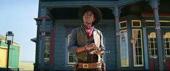 Movie still from “The Harder They Fall” (2021), directed by Jeymes Samuel – A man in a cowboy hat and vest holding a gun; Medium shot, Low angle
