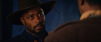 Movie still from “The Harder They Fall” (2021), directed by Jeymes Samuel – A person wearing a hat; Close Up shot, Over the shoulder angle