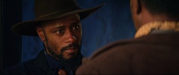Movie still from “The Harder They Fall” (2021), directed by Jeymes Samuel – A person wearing a hat; Close Up shot, Over the shoulder angle