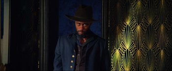 Movie still from “The Harder They Fall” (2021), directed by Jeymes Samuel – A man wearing a hat and a blue jacket; Medium shot, Low angle