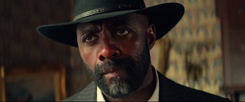 Movie still from “The Harder They Fall” (2021), directed by Jeymes Samuel – A person wearing a hat and a suit; Close Up shot, Low angle