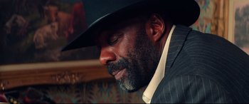 Movie still from “The Harder They Fall” (2021), directed by Jeymes Samuel – A man in a suit wearing a hat and looking to his left; Close Up shot, Low angle