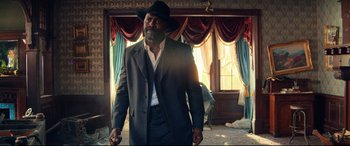 Movie still from “The Harder They Fall” (2021), directed by Jeymes Samuel – A man in a suit and hat is holding a gun; Medium shot, Low angle