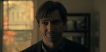Movie still from “The Haunting of Hill House” (2018), directed by Mike Flanagan – A person wearing a suit and tie; Close Up shot, Over the shoulder angle