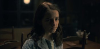 Movie still from “The Haunting of Hill House” (2018), directed by Mike Flanagan – A young girl is sitting in front of a window at night; Close Up shot, High angle